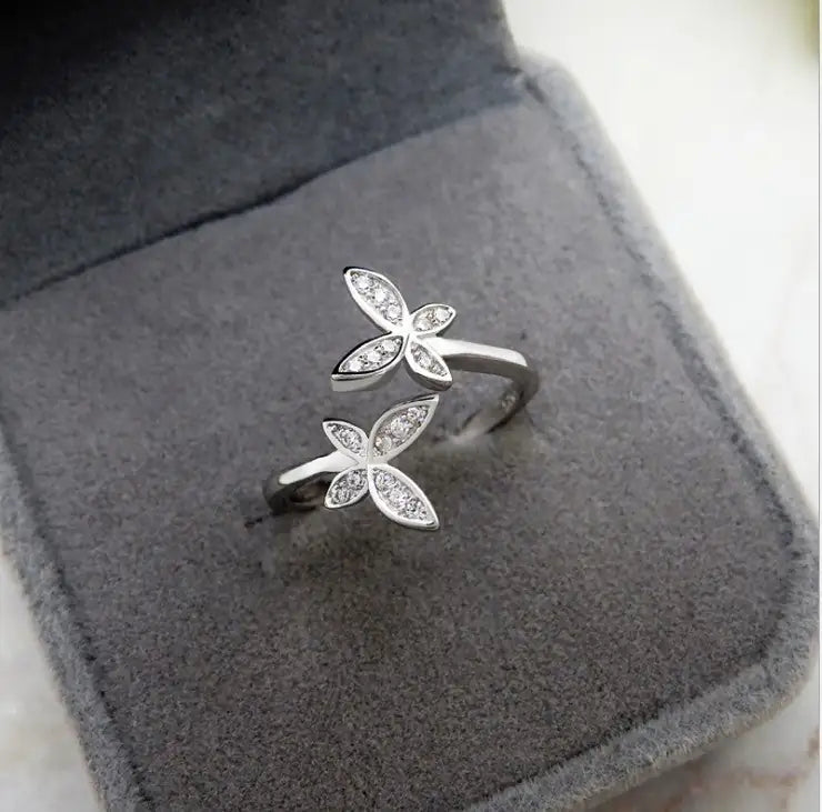 Silver ring with floral design on a gray cushion