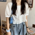 Person wearing a white blouse and blue denim shorts in an indoor setting.
